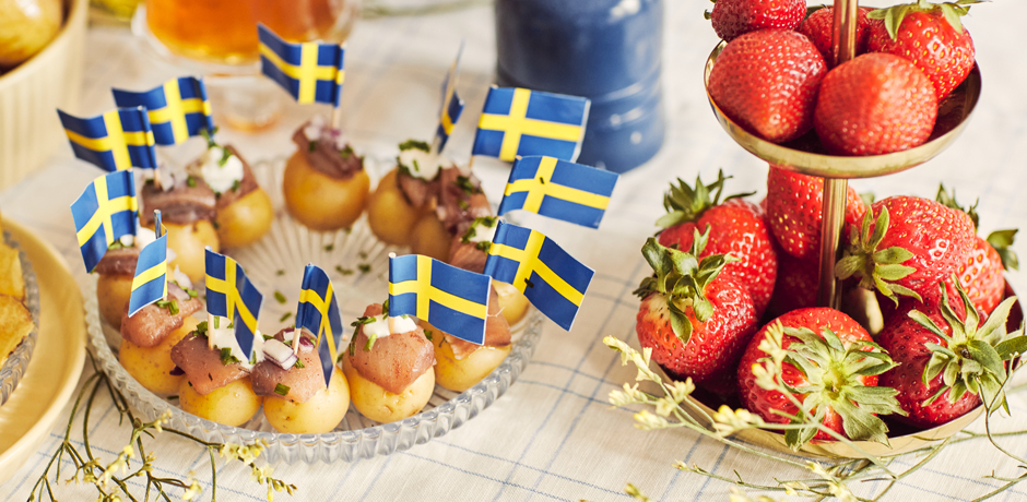 Svenska flaggor i potatisar med sill på ett fat.