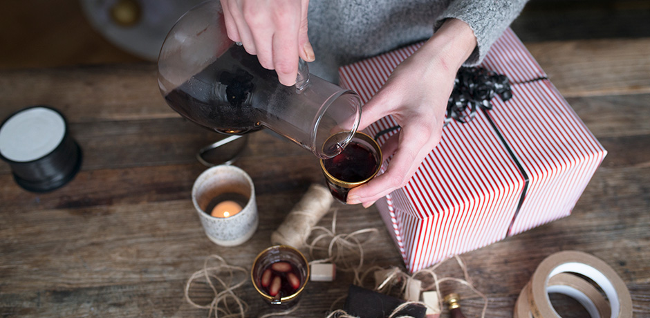 Person häller upp glögg från en tillbringare i glas