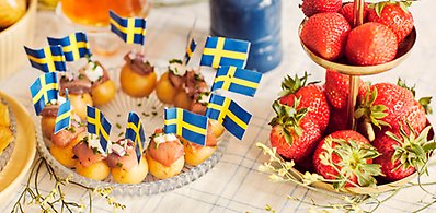 Svenska flaggor i potatisar med sill på ett fat.